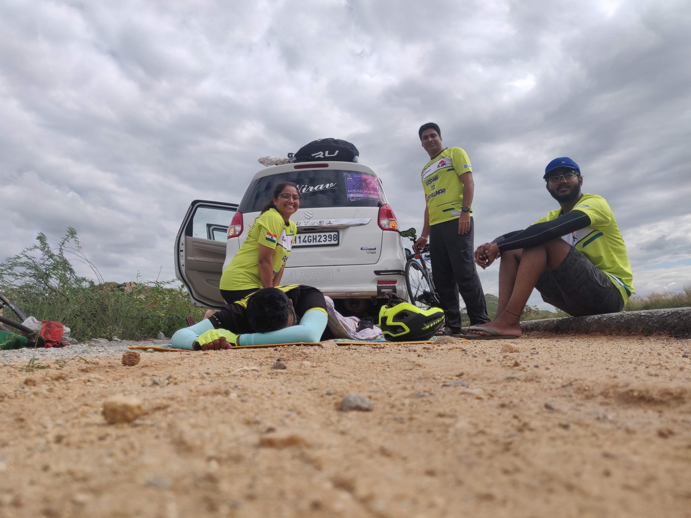 Jyoti Tripathi laughing while stretching out Bharat Pannu after a stage of the Kashmir to Kanyakumari record, crew gathered around the support vehicle