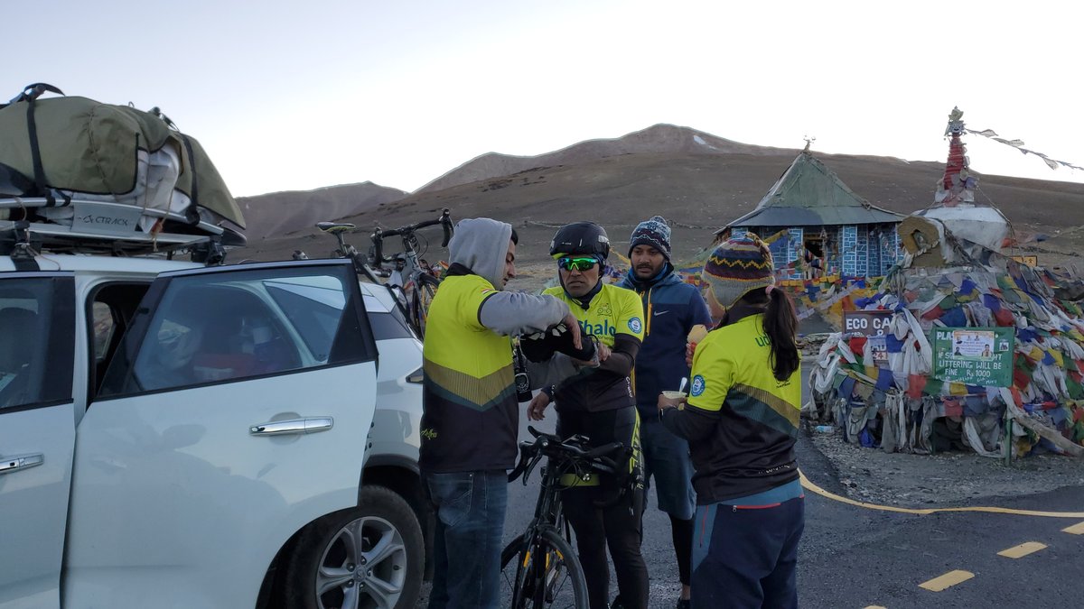 Team Pannu crew gathered at a high mountain pass with prayer flags during the Leh to Manali record attempt